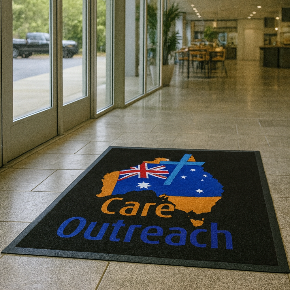 Floor mat with 'Care Outreach' design in a modern building entrance