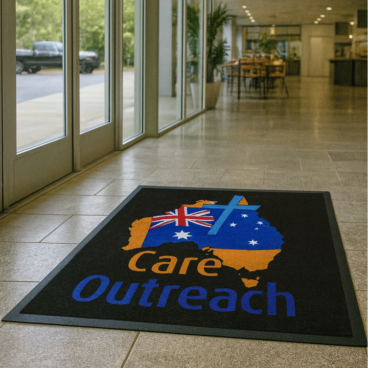 Floor mat with 'Care Outreach' design in a modern building entrance
